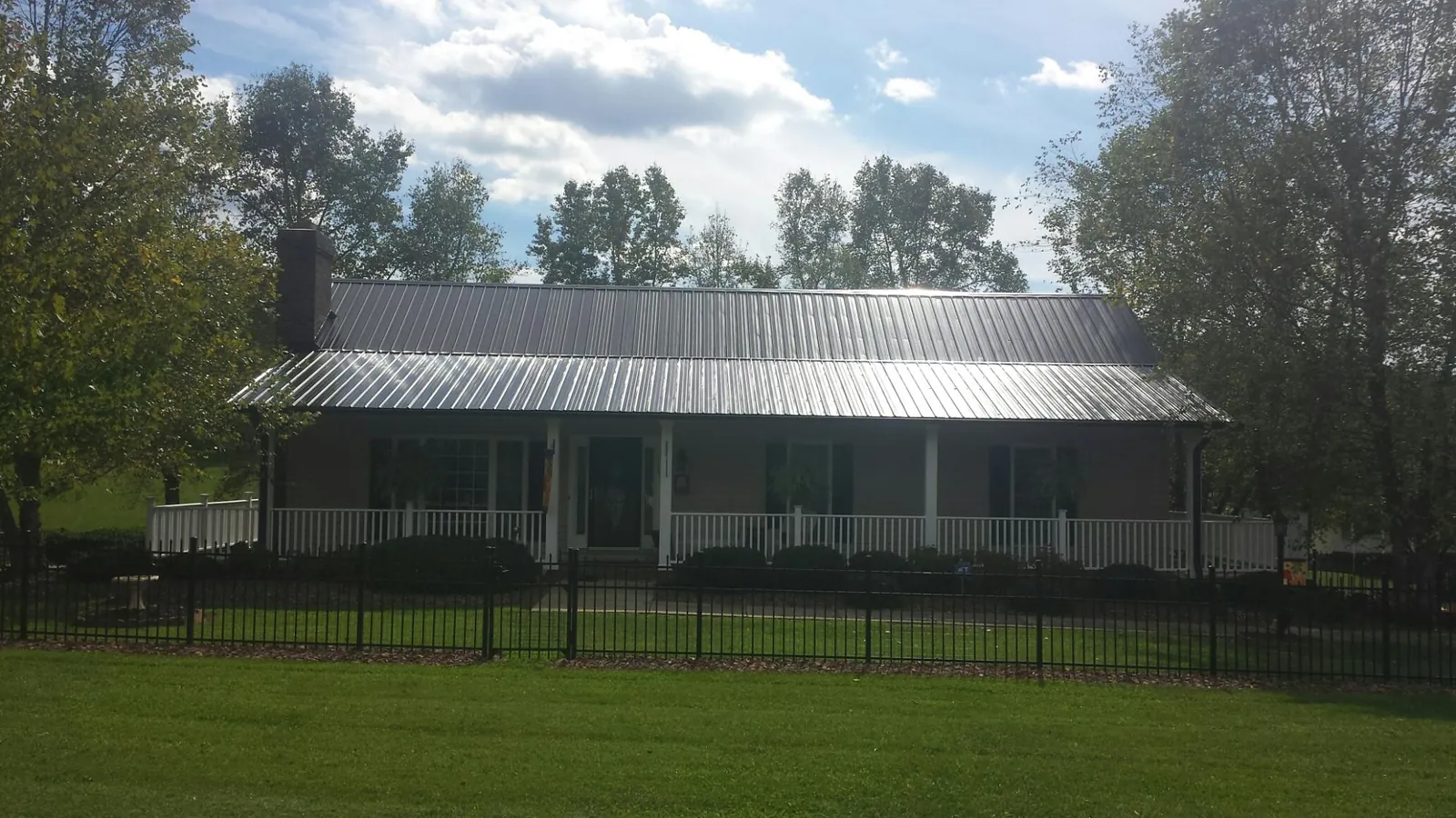 Gray metal roof on a brick ranch with a full width front porch — Gutter Guard Installation work by our crew in Galveston